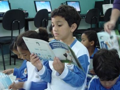 Aluno da escola Martins Fontes lendo o "Livro do Aluno", cartilha de educa&ccedil;&atilde;o ambiental marinha do Projeto Albatroz